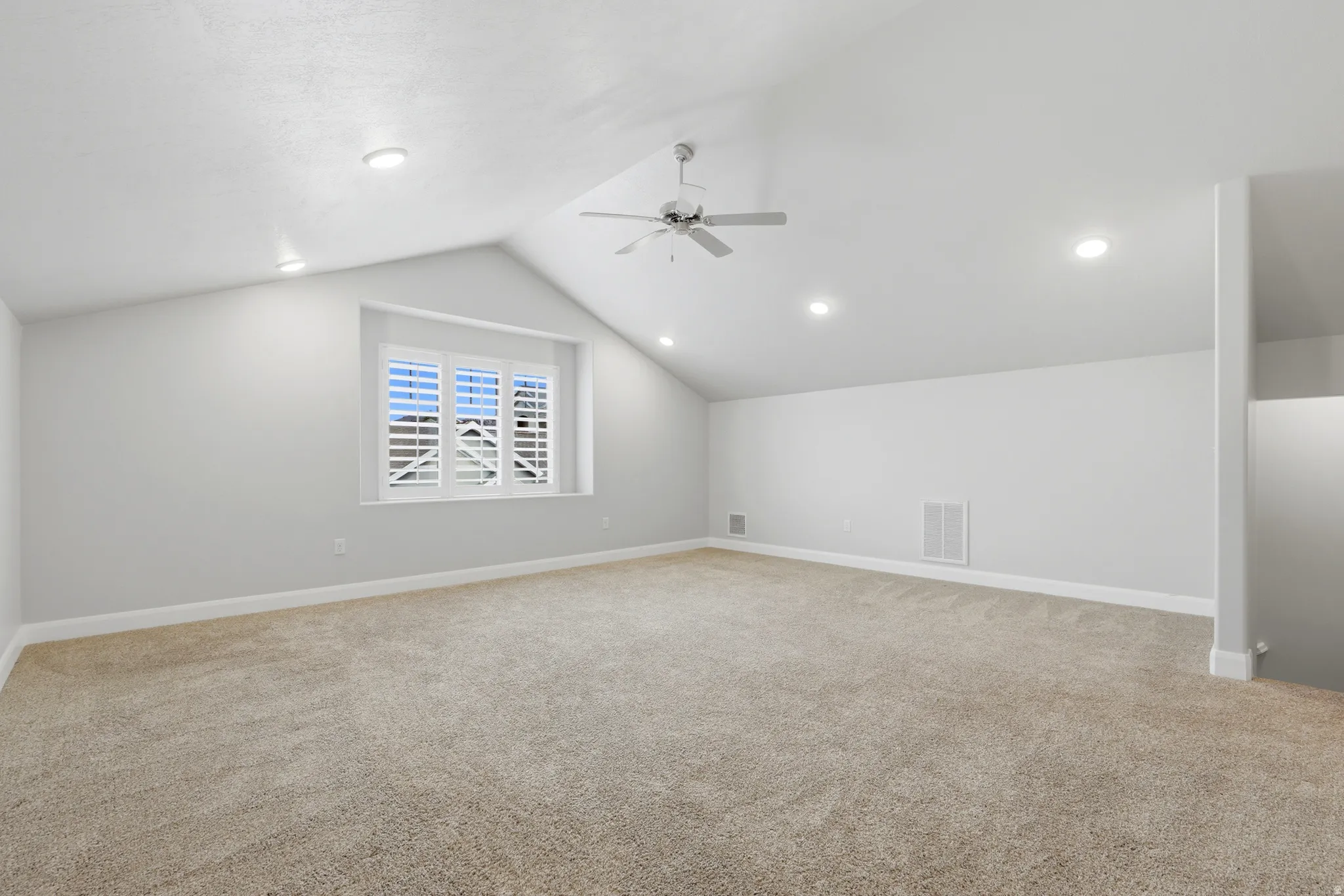 Spacious room featuring a vaulted ceiling with recessed lighting and a ceiling fan