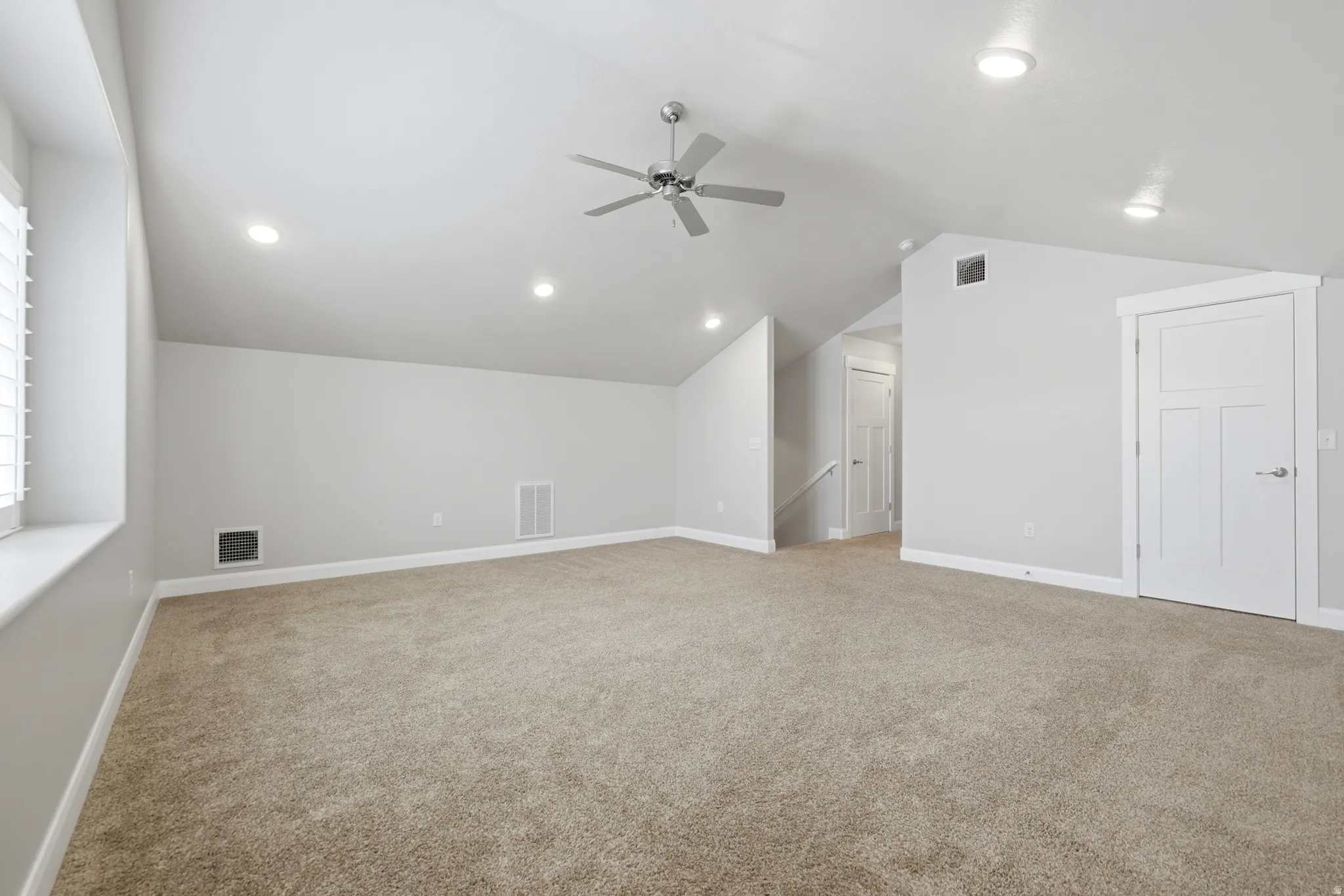 Carpeted room with a vaulted ceiling, recessed lighting, and a ceiling fan