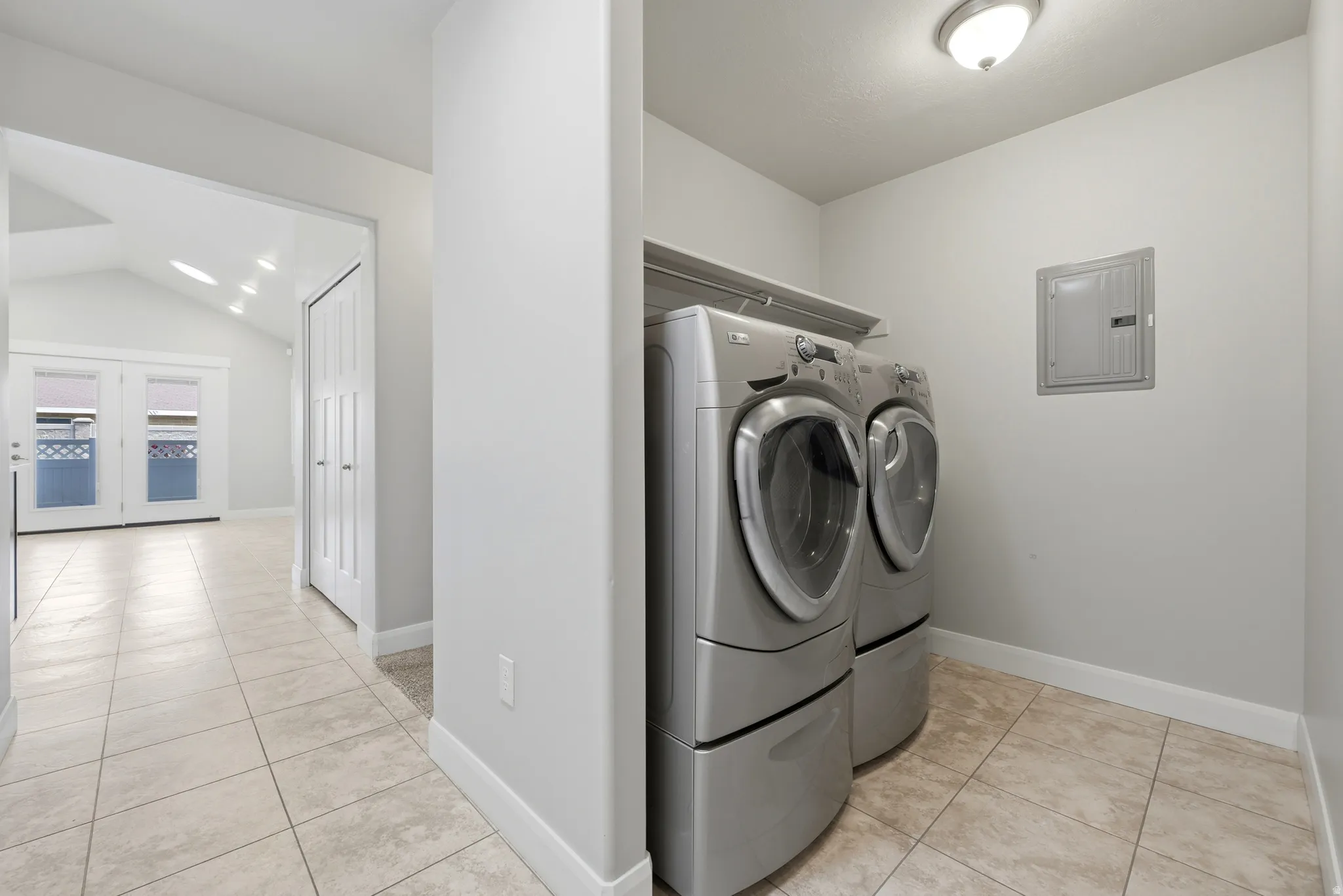 Dedicated laundry space featuring tile flooring and overhead shelving