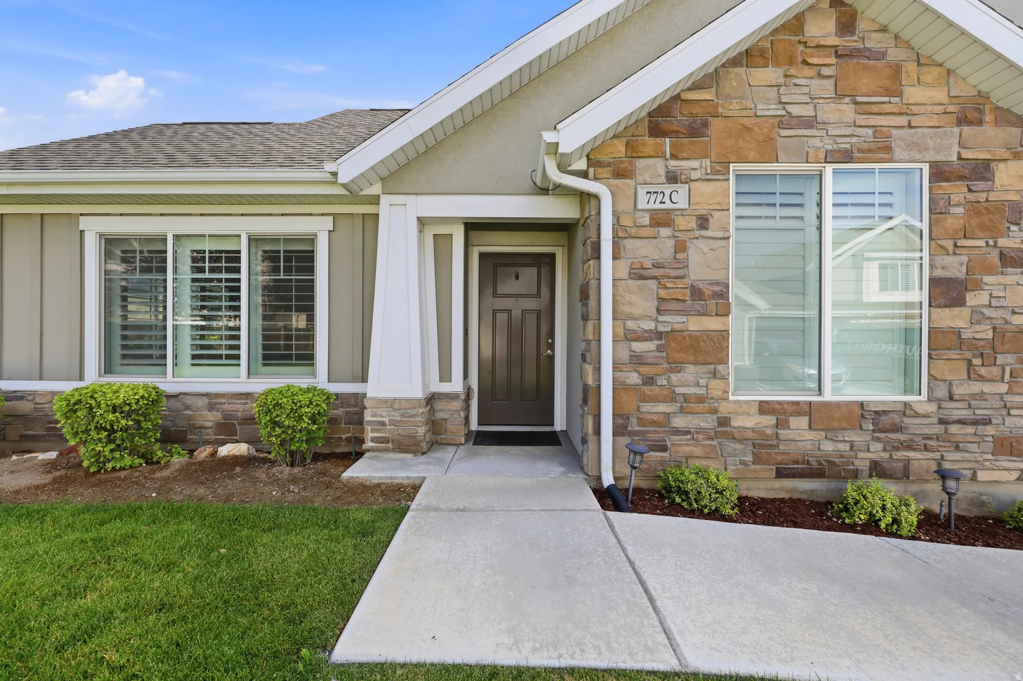 Stone veneer and vertical siding exterior with a dark panel front door