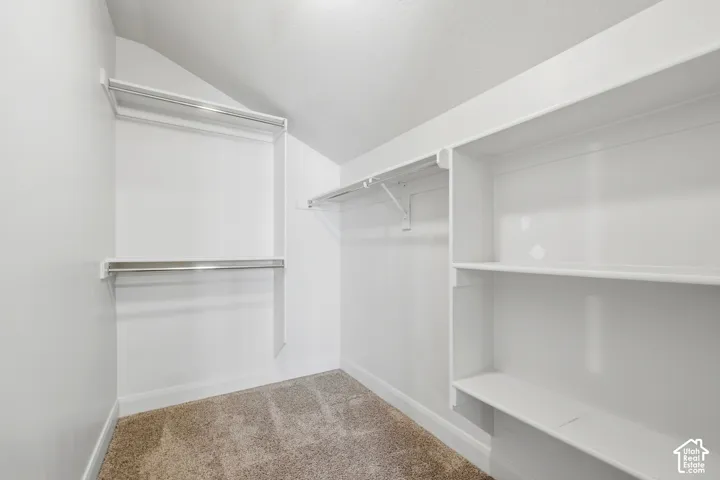 Spacious closet featuring white walls, white shelving, and chrome hanging rods
