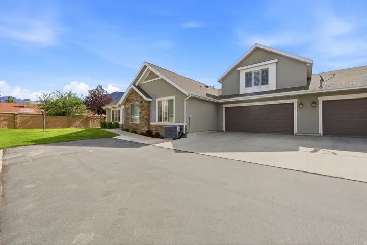 Stucco exterior featuring stone accents, multiple garage bays, and a dormer window