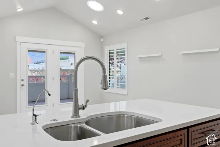 Dual basin stainless steel sink with a high-arch faucet, white countertop, and dark wood-finish cabinetry