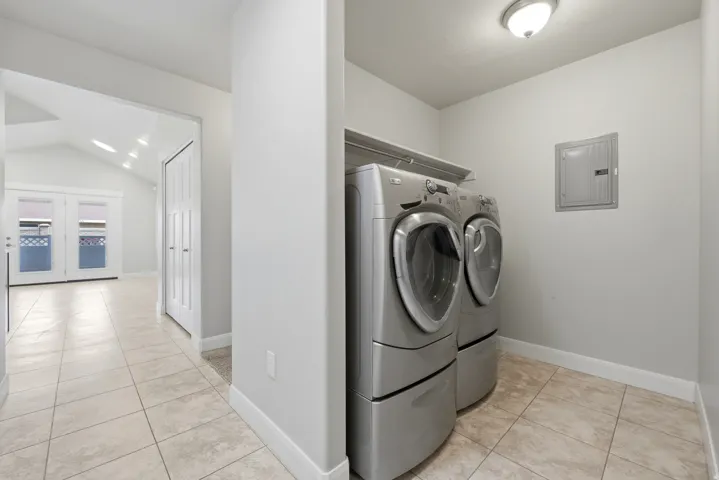 Dedicated laundry space featuring tile flooring and overhead shelving