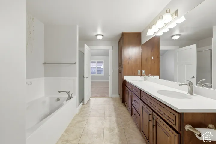 Double vanity with white countertops, wood-finish cabinetry, and a full-width mirror