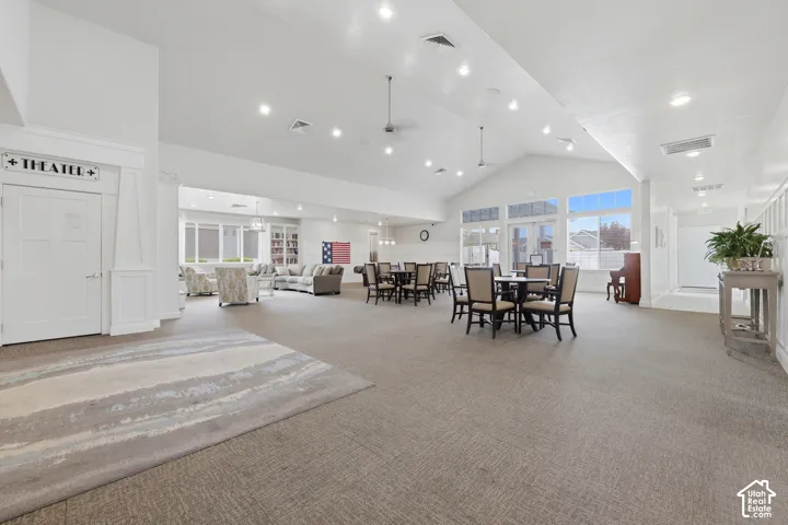 Spacious common area featuring vaulted ceilings, recessed lighting, large windows, and carpeted flooring