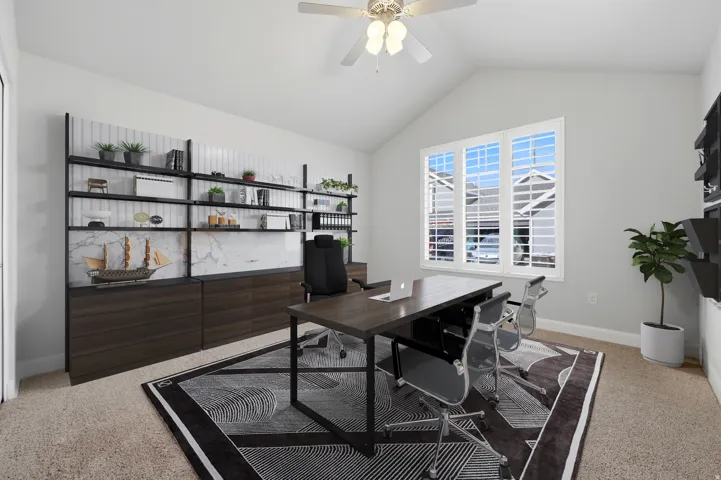 Vaulted ceiling with a ceiling fan, built-in shelving with marble-effect panels, built-in wood-finish cabinetry, and a large three-panel window with louvered shutters