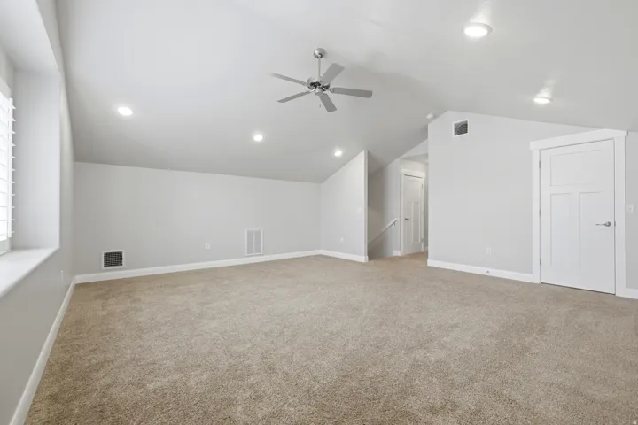 Carpeted room with a vaulted ceiling, recessed lighting, and a ceiling fan