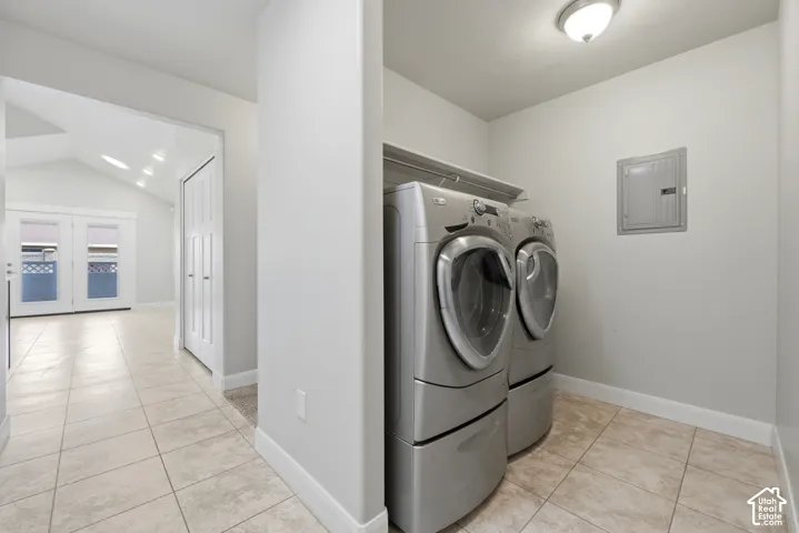 Dedicated laundry space featuring tile flooring and overhead shelving