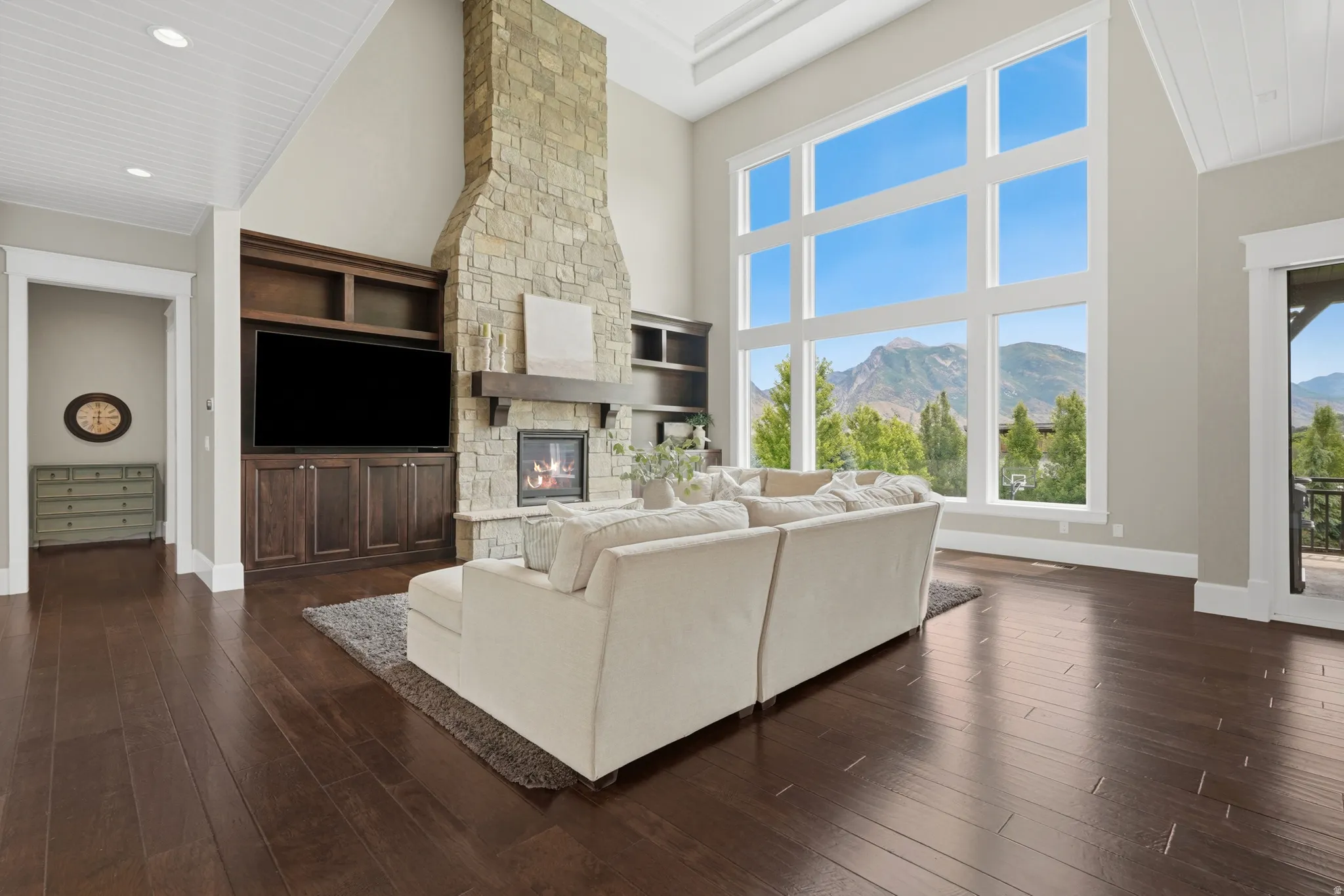 Great room featuring a floor-to-ceiling stone fireplace, built-in media cabinetry, and expansive window wall
