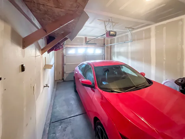 Garage interior featuring an automatic overhead door, concrete flooring, and an overhead storage shelf