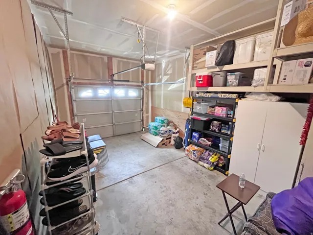 Attached garage featuring a concrete floor, automatic garage door opener, and integrated shelving for organization