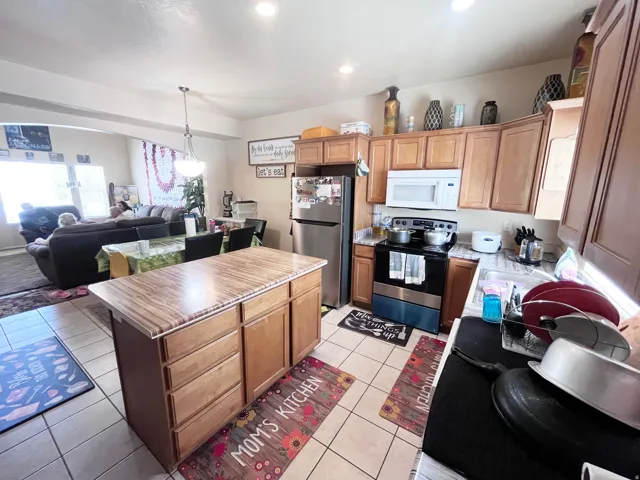 Kitchen featuring wood-finish cabinetry, a central island with a wood-finish countertop, stainless steel appliances, and tile flooring