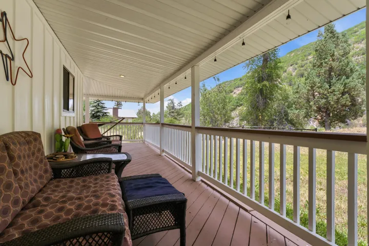 Expansive covered porch featuring a wood-finish deck, white railing, and exterior paneling