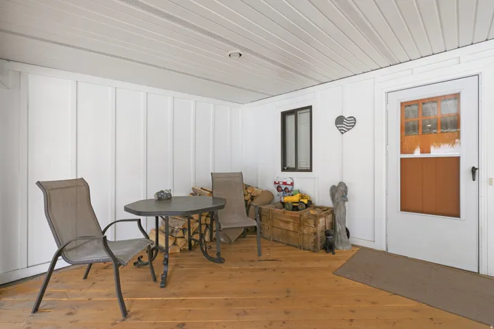 Covered porch with wood-finish flooring, white board and batten wall paneling, and a white plank ceiling