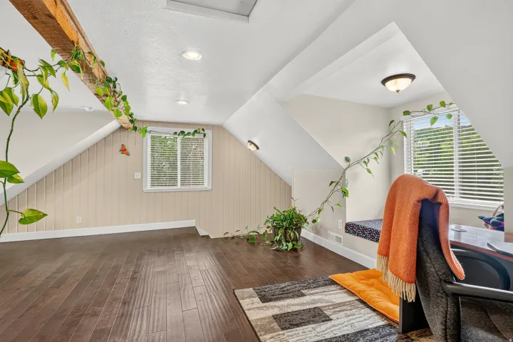 Expansive attic space featuring rich wood-finish flooring and a prominent exposed wood beam