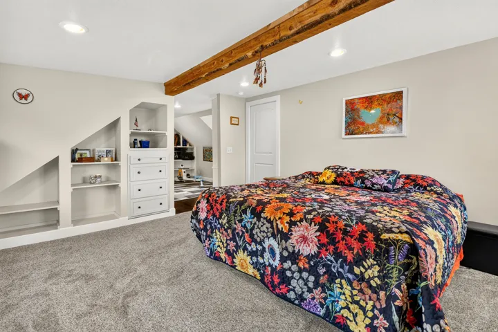 Carpeted room featuring a prominent exposed wood beam, recessed lighting, and a white two-panel door