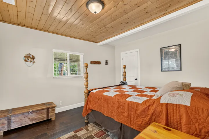 Room featuring a wood-panel ceiling, dark wood-finish flooring, and light-toned walls