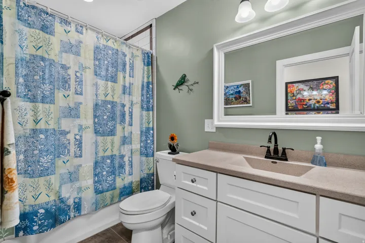 Bathroom featuring a single vanity with an integrated sink, white cabinetry, and a framed mirror