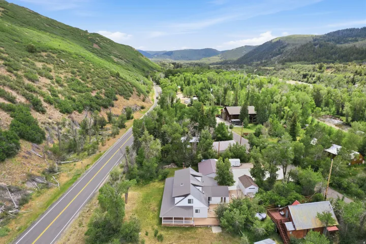 Aerial perspective showcasing a property nestled within a mountainous, tree-filled landscape