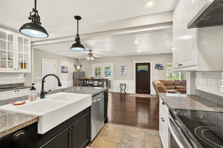 Gourmet kitchen with granite countertops, white farmhouse sink, stainless steel appliances, and white subway tile backsplash