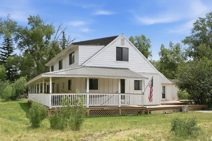 White two-story residence featuring a full-length covered porch with a metal roof and white railing