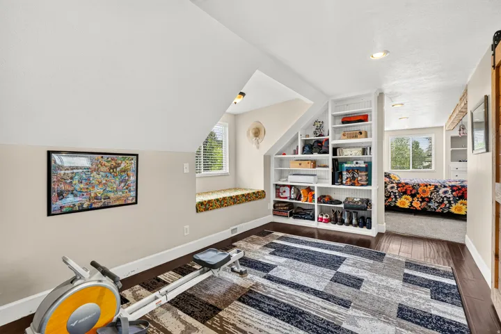 Sloped ceiling room featuring dark wood-finish flooring, a built-in window seat, recessed lighting, and extensive built-in shelving