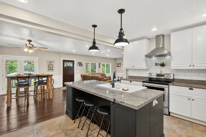 Kitchen island featuring a granite-style countertop, undermount sink, and pendant lighting