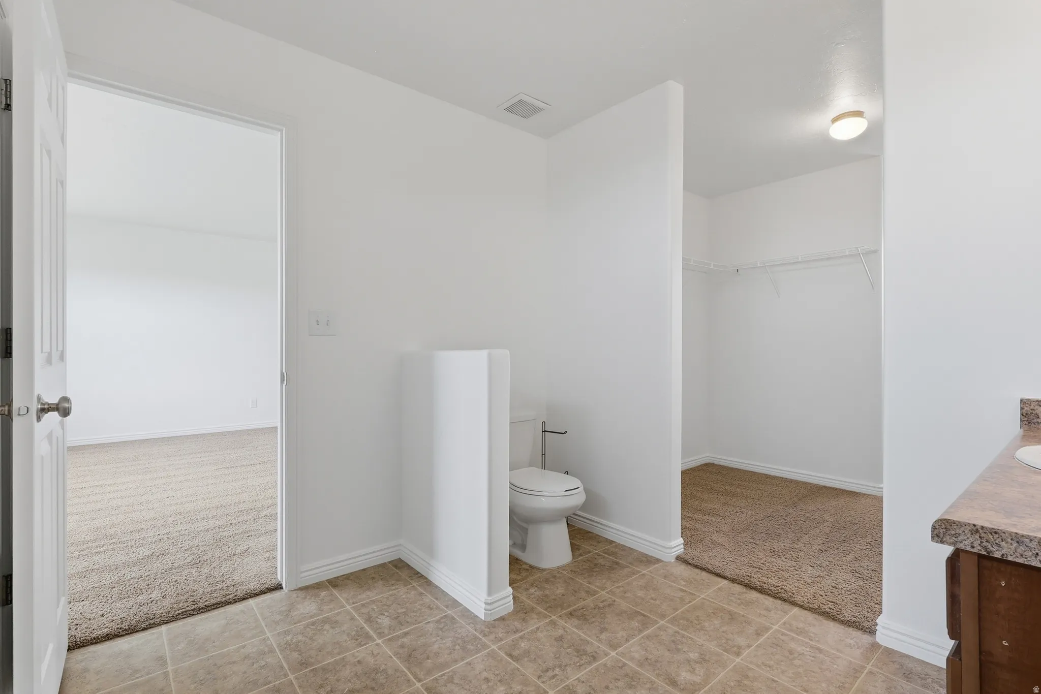 Bathroom featuring neutral tile flooring and a white toilet