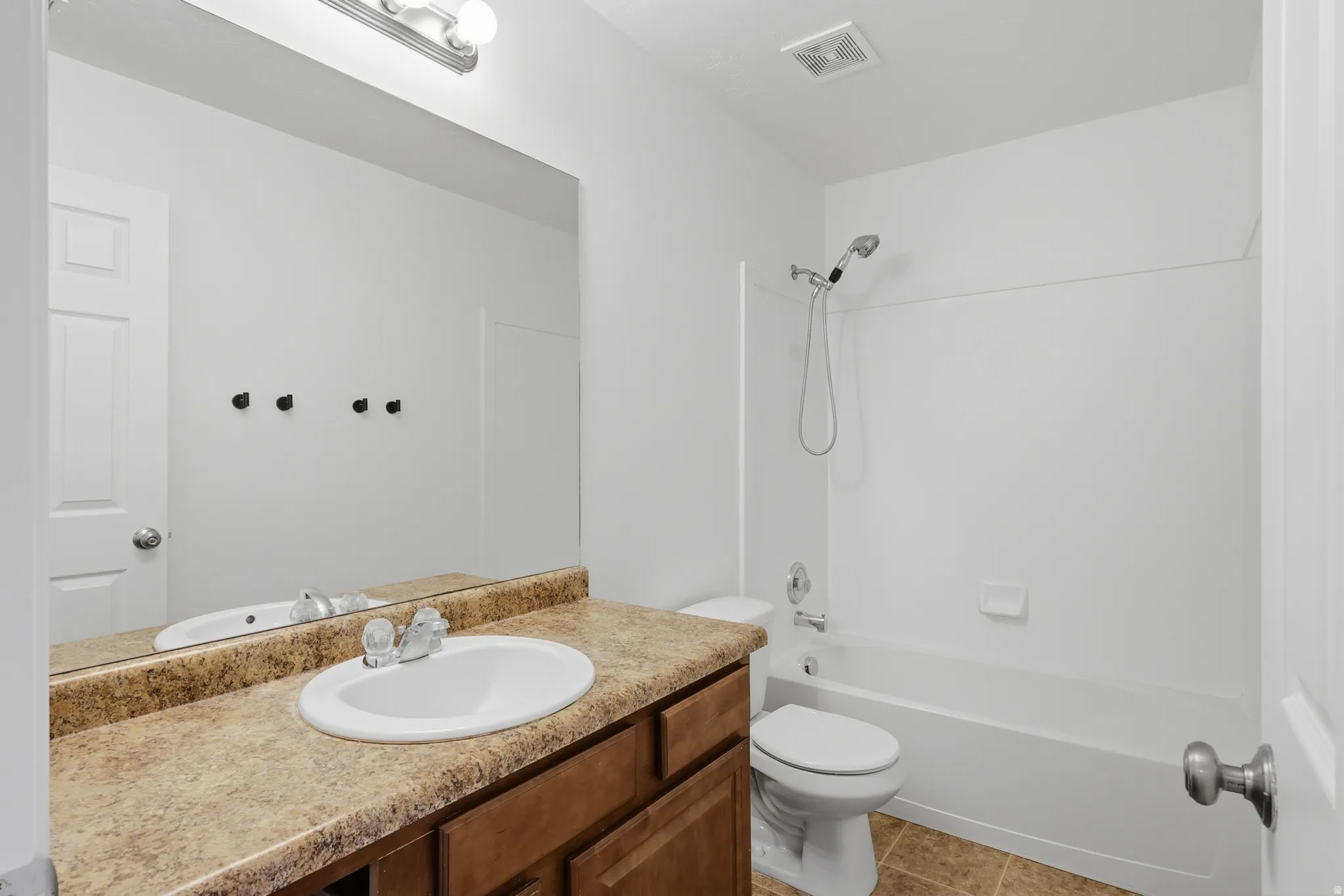 Bathroom featuring a vanity with a laminate countertop, integrated sink, and wood-finish cabinetry