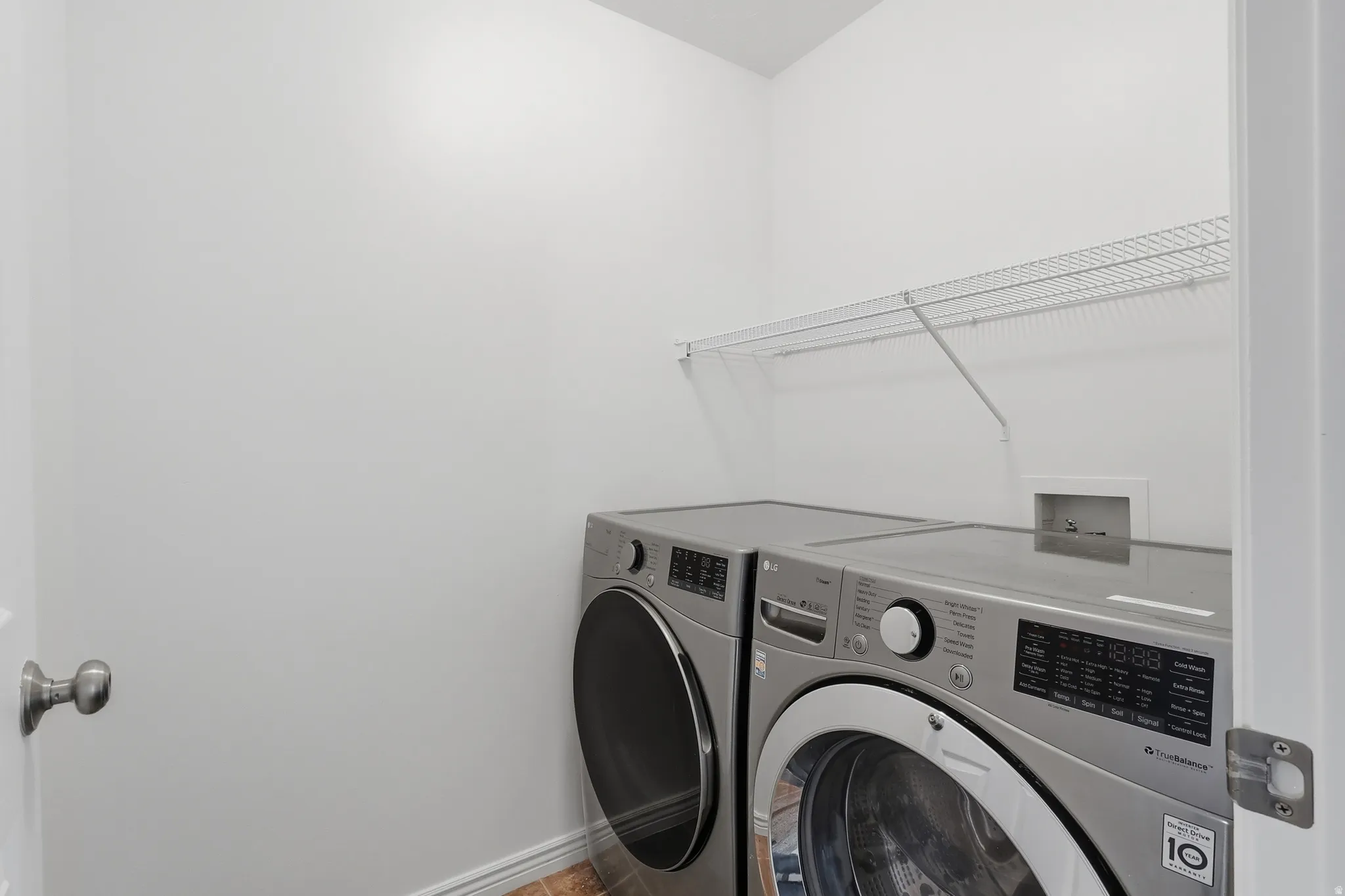 Dedicated laundry area featuring a white wire shelf, light-colored walls, and wood-finish flooring