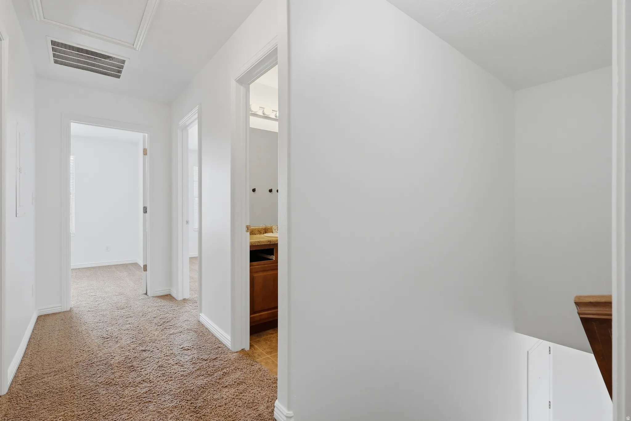 Carpeted hallway with white walls and trim, leading to multiple doorways