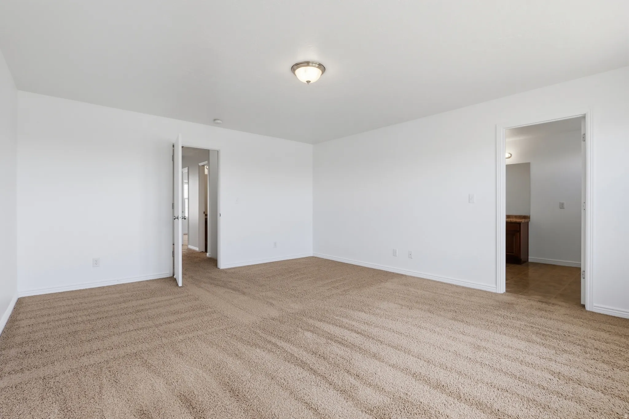 Spacious room with plush carpet flooring and white painted walls