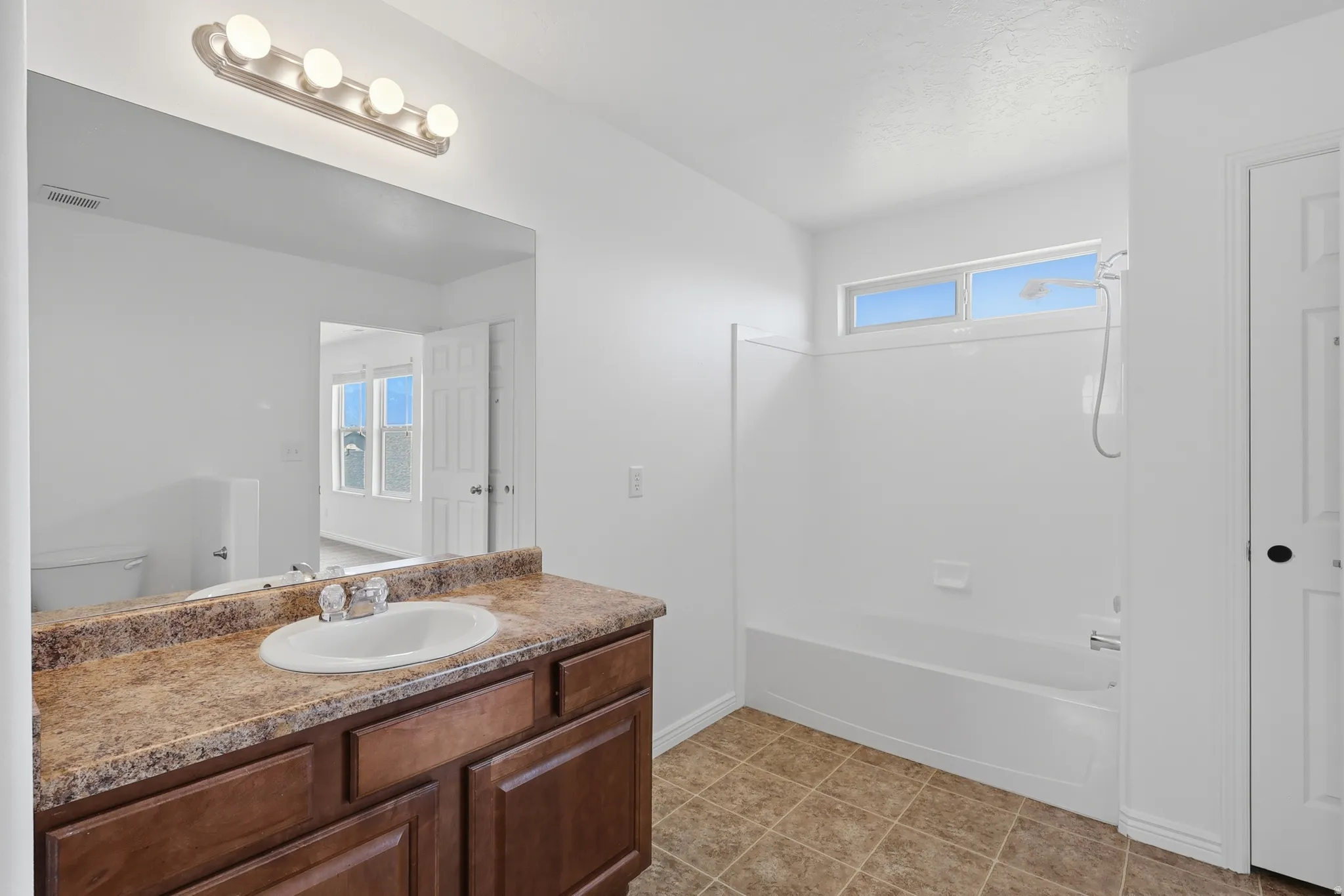 Bathroom featuring a vanity with a laminate countertop, integrated sink, and wood-finish cabinetry