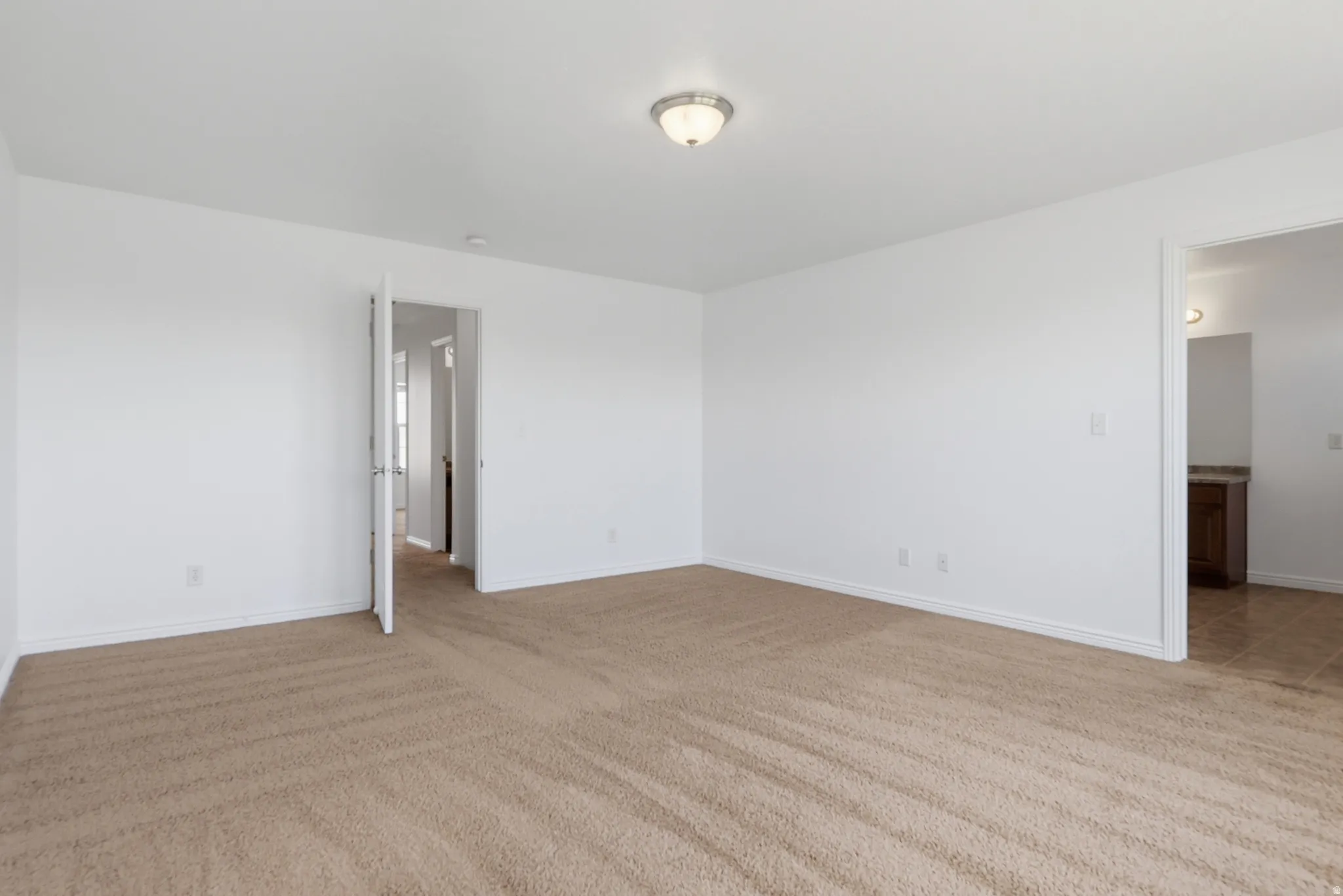 Spacious room featuring neutral carpeting and white wall paint