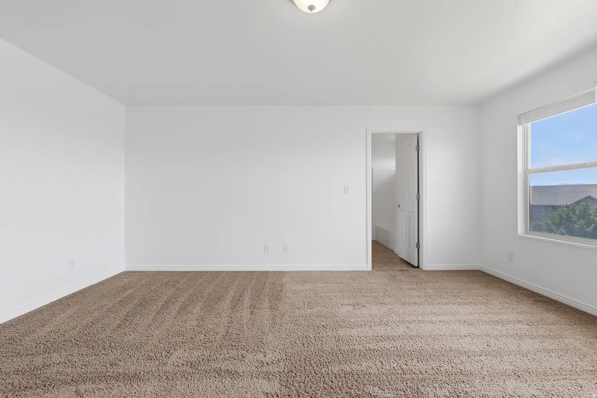 Spacious room featuring neutral carpeting and white wall finishes