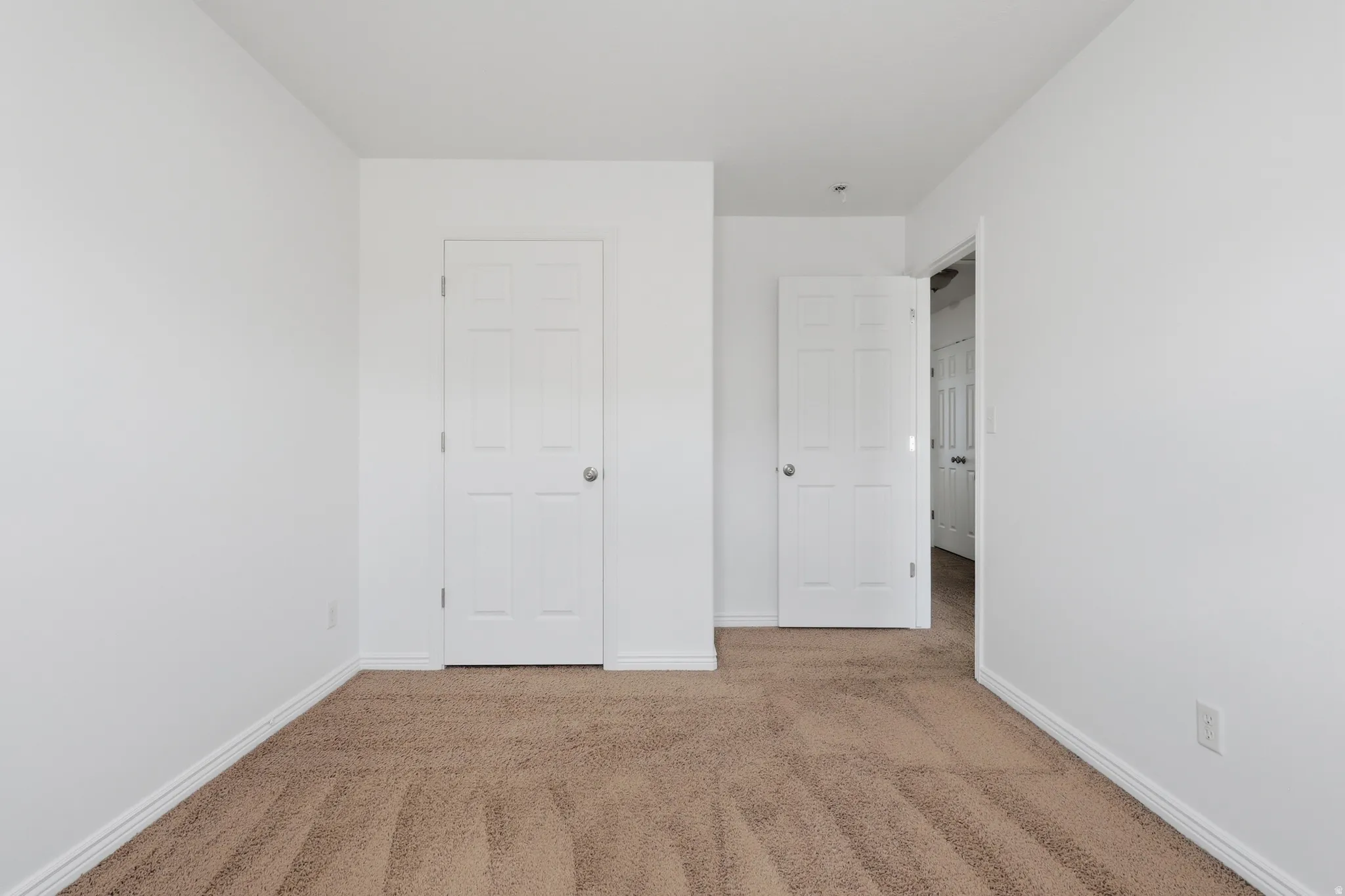 Neutral color palette featuring light beige carpet flooring and white walls