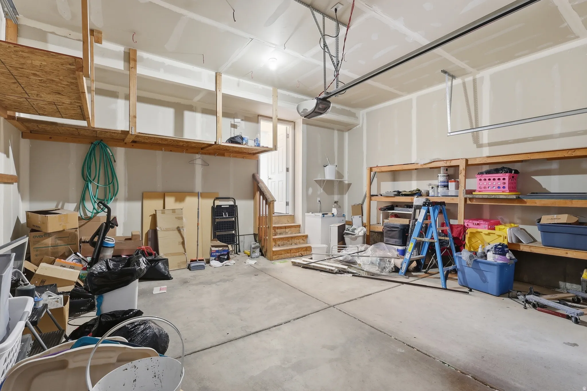 Spacious garage featuring concrete flooring, built-in shelving, overhead storage, and an automatic garage door opener