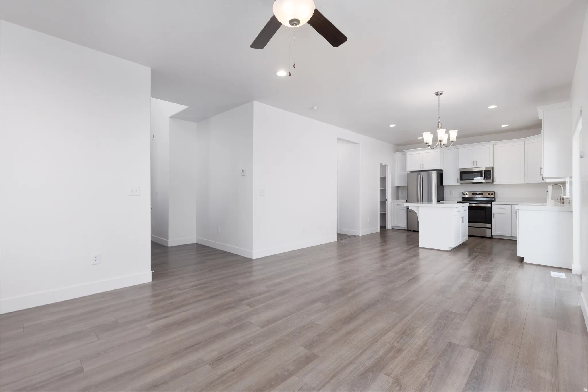 Open-concept living space featuring wood-finish flooring, recessed lighting, and a ceiling fan