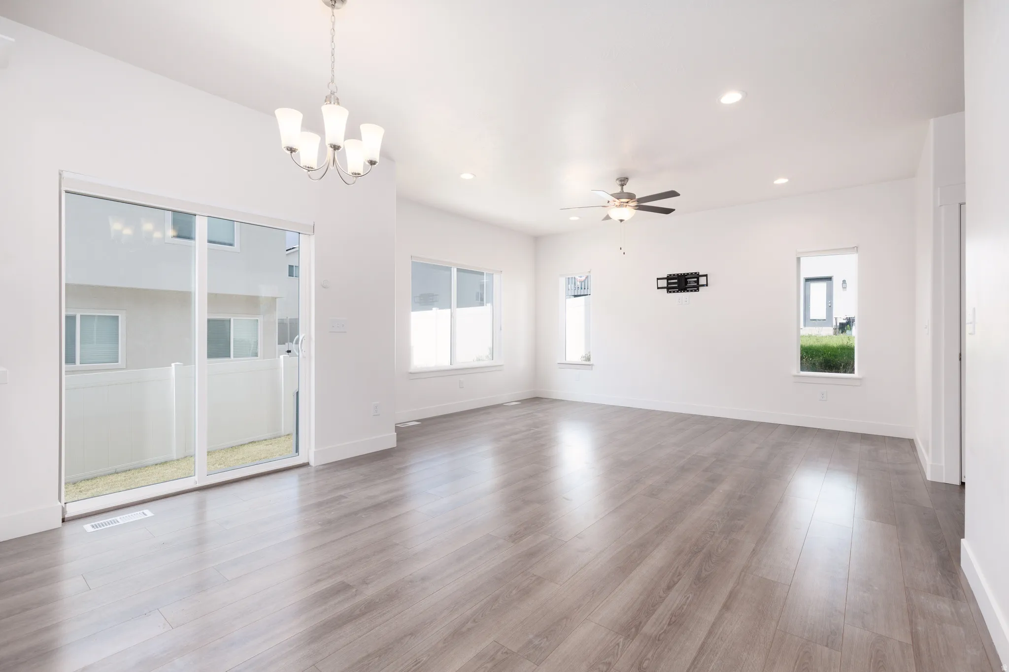 Spacious room featuring light wood-finish flooring, white walls, and multiple windows