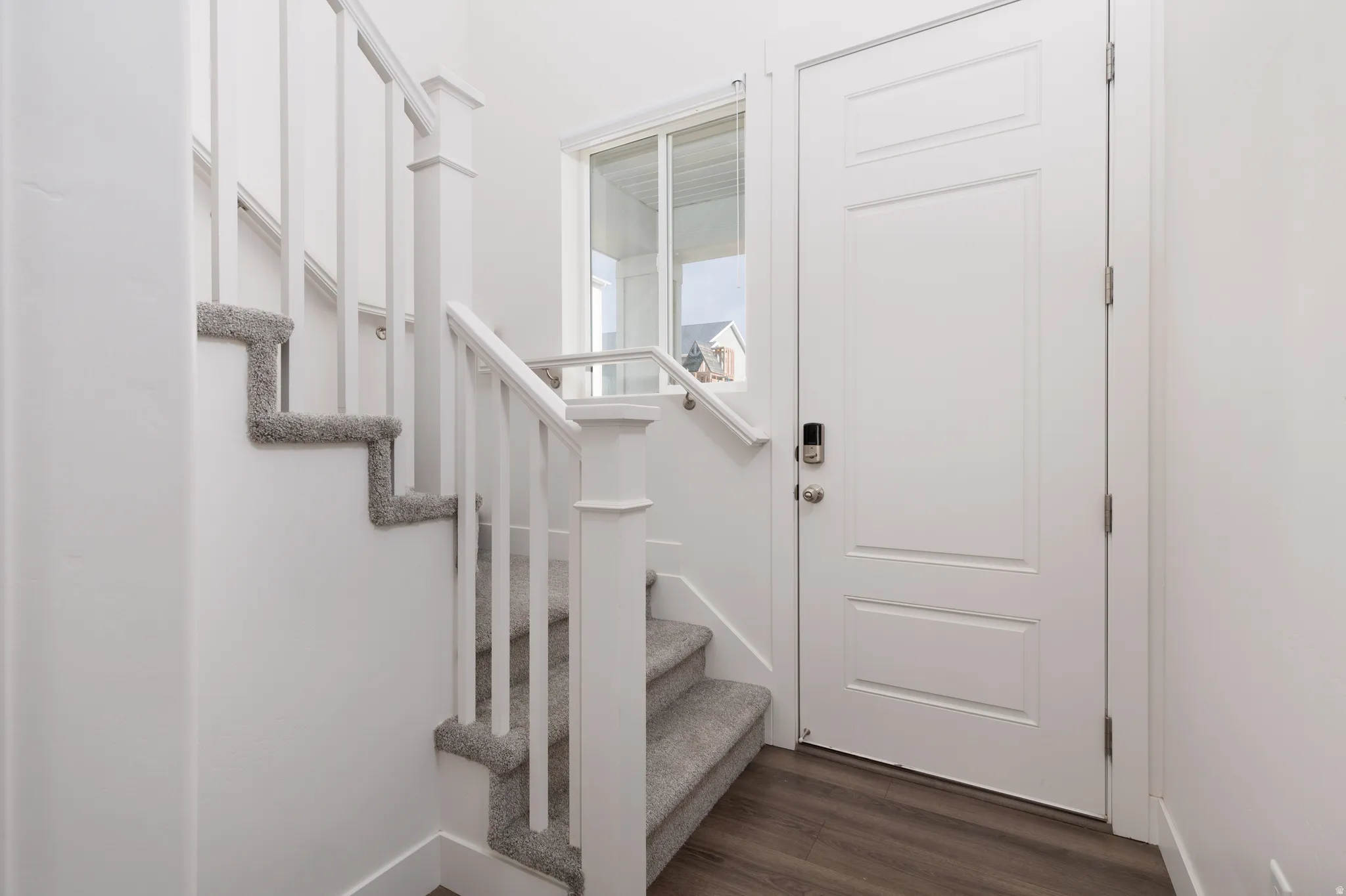 Entryway featuring wood-finish flooring and a contemporary white door with a digital lock