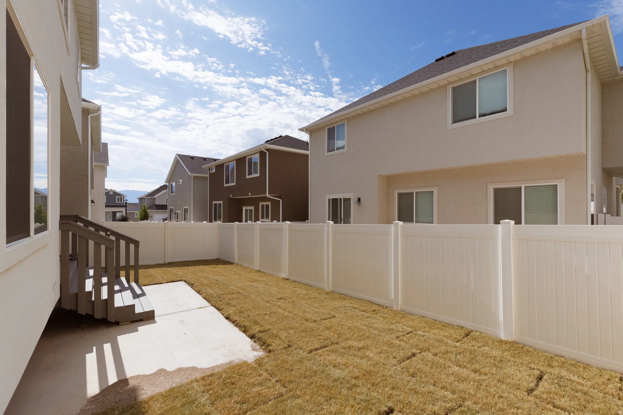 Enclosed backyard featuring a vinyl privacy fence, a concrete patio, and a wooden staircase