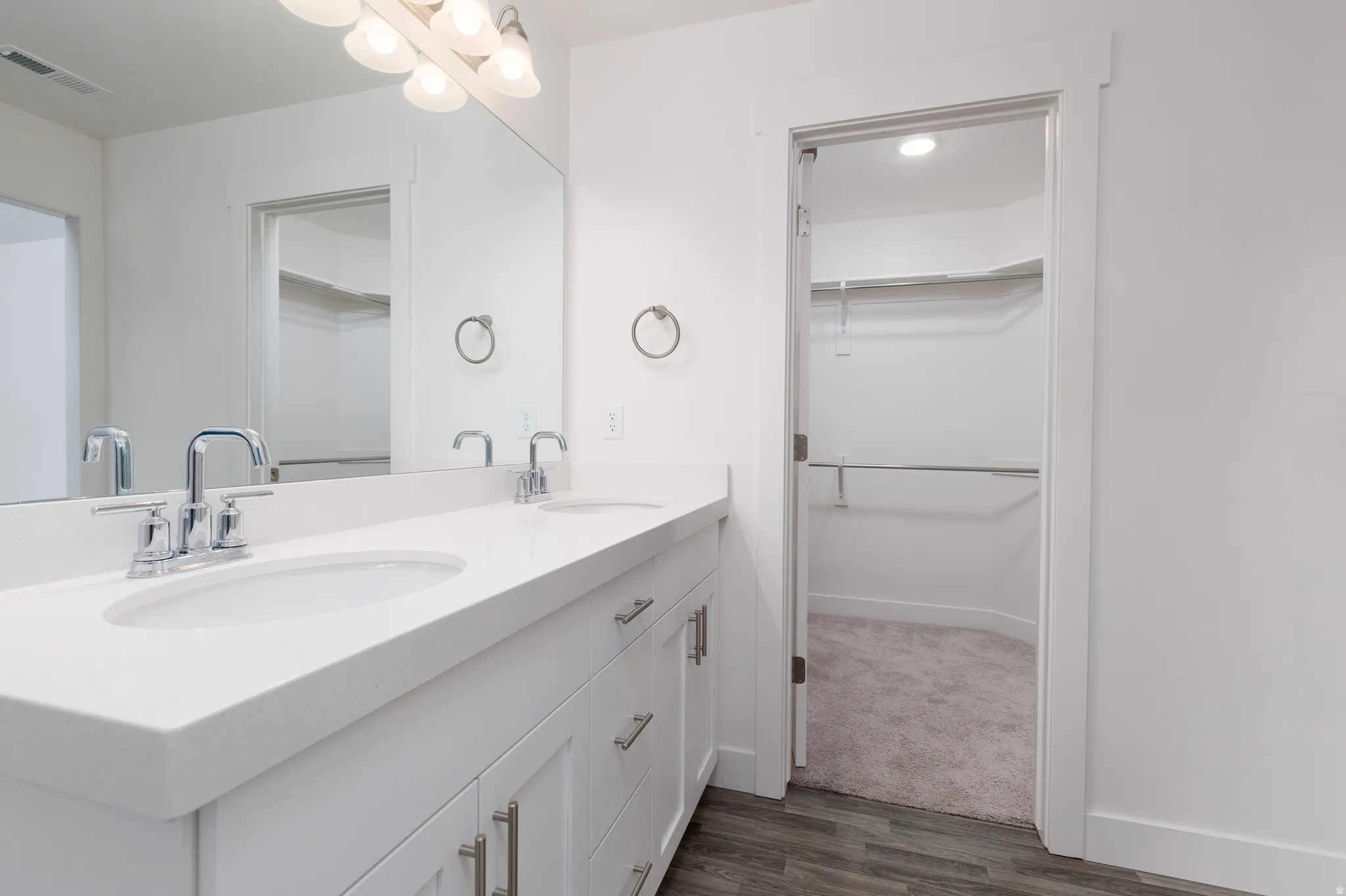 Double vanity featuring white countertops, undermount sinks, and chrome faucets