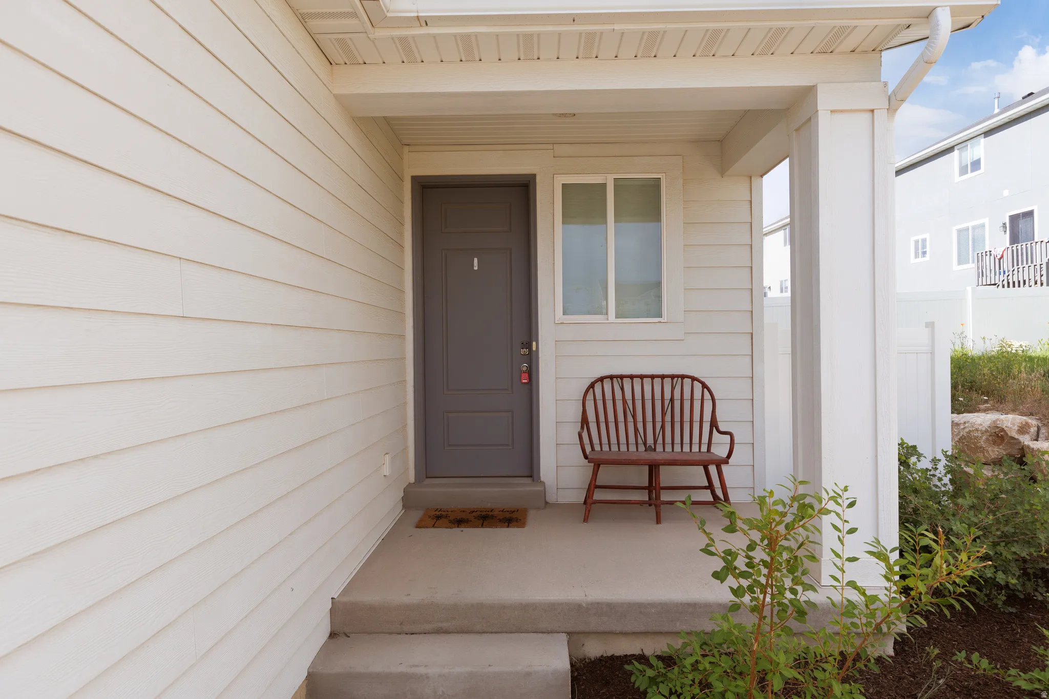 Inviting covered porch entry with an opaque paneled door and light-toned horizontal siding