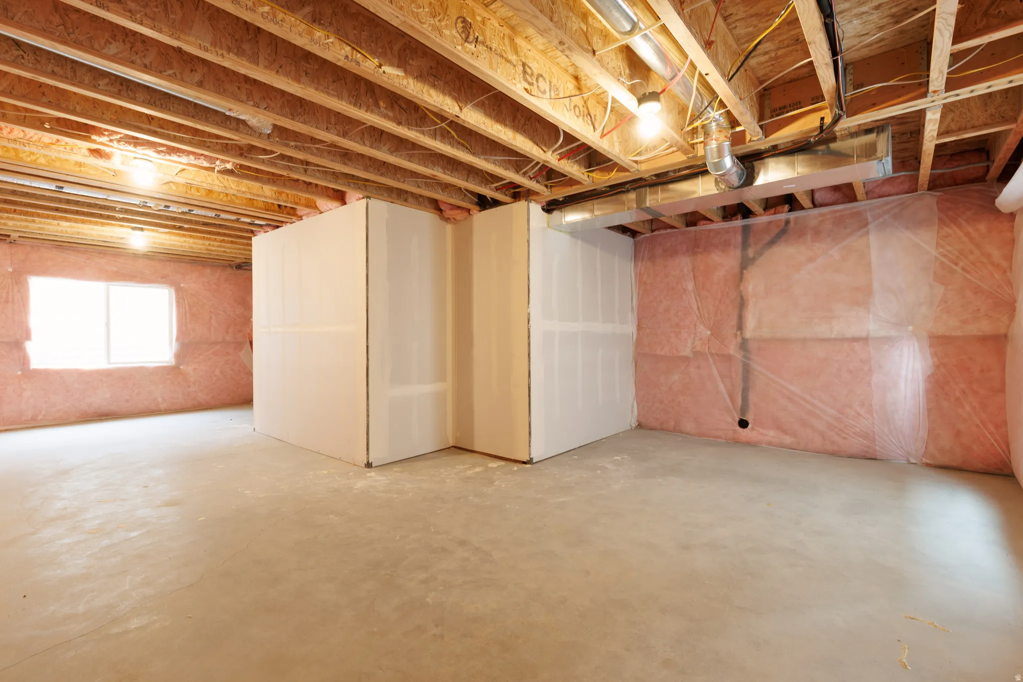 Unfinished basement with exposed ceiling joists, concrete flooring, and insulated perimeter walls