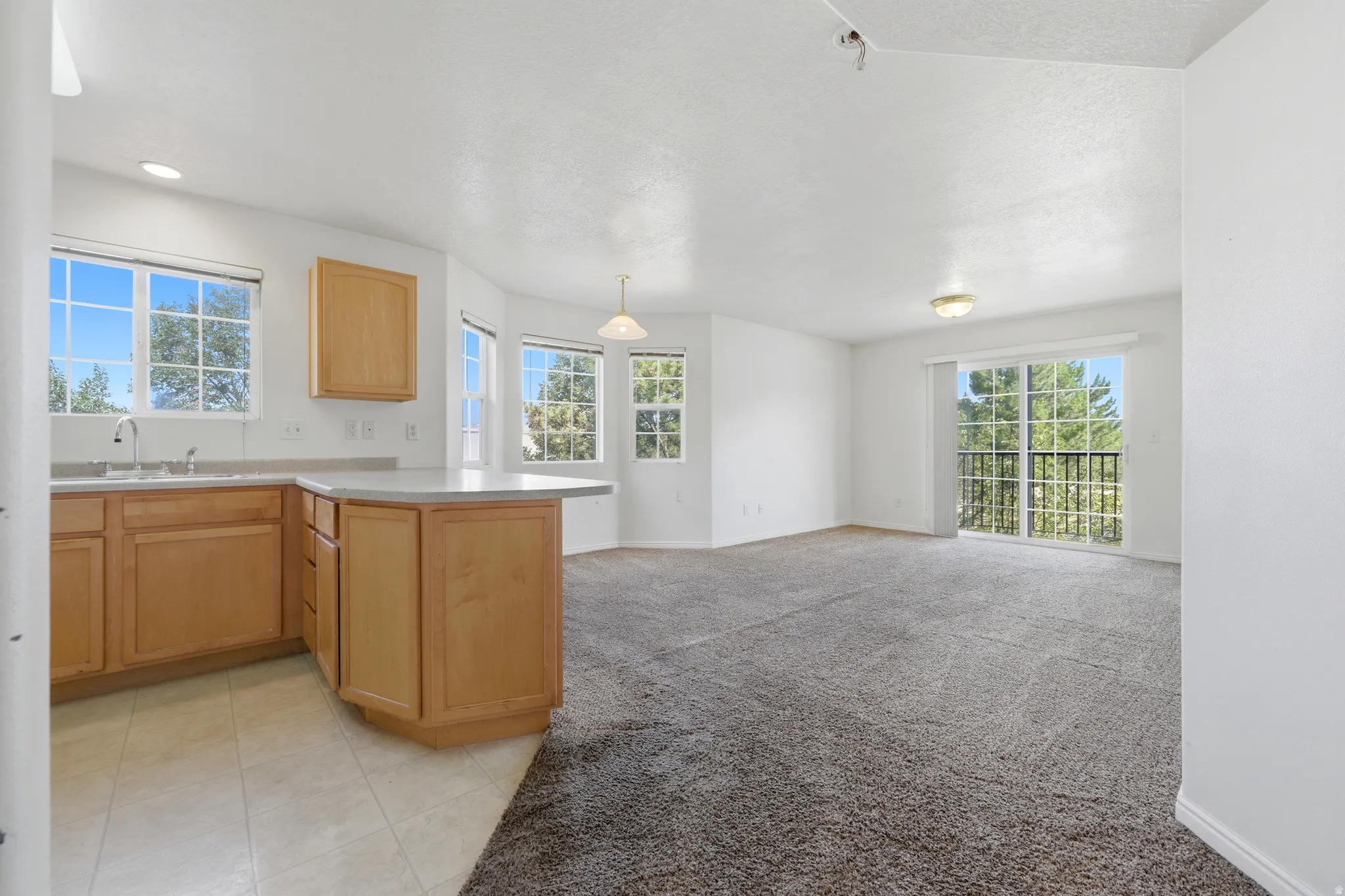 Open-concept living space featuring a kitchen with light wood cabinetry and a peninsula countertop