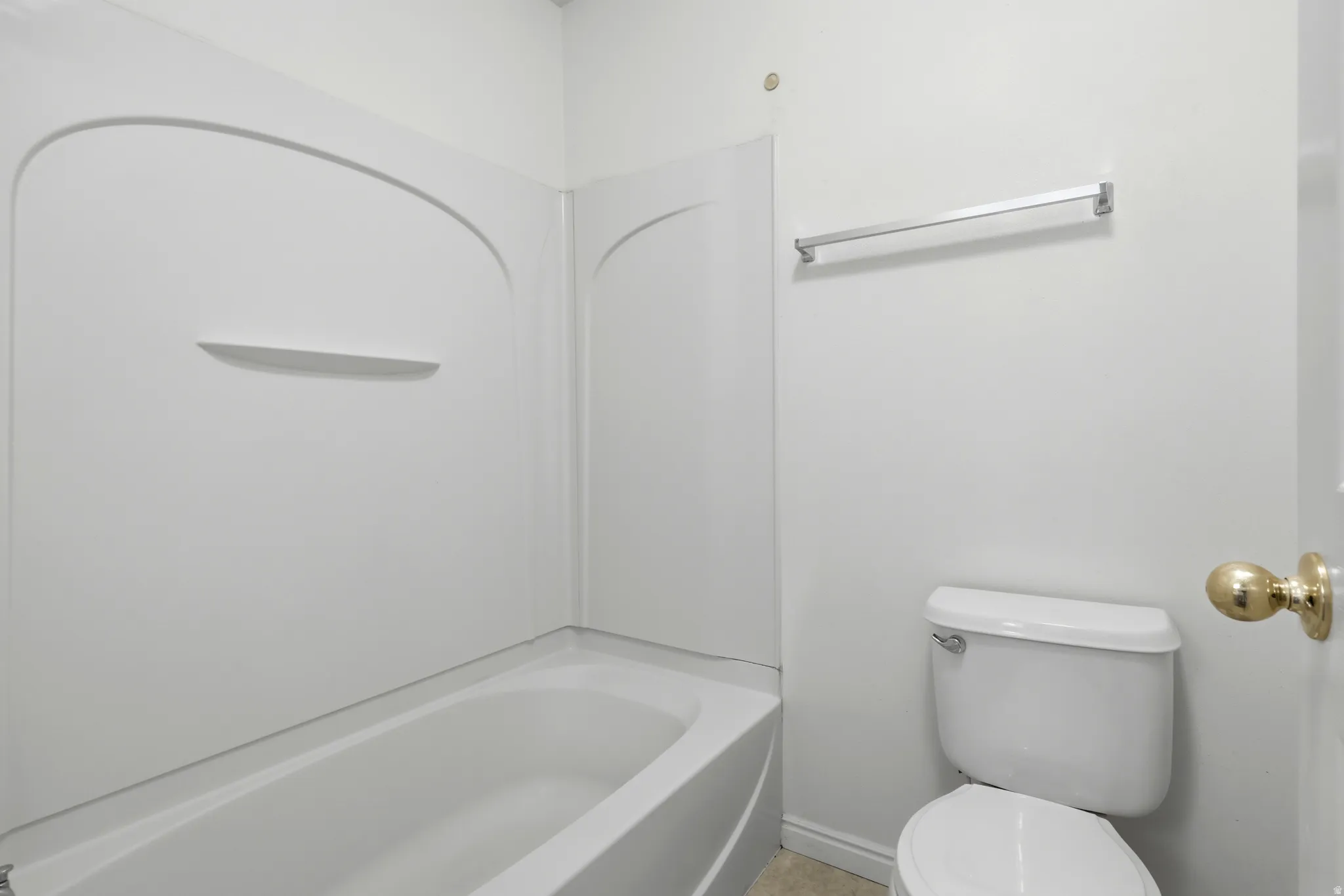 White bathtub and shower surround with an integrated shelf