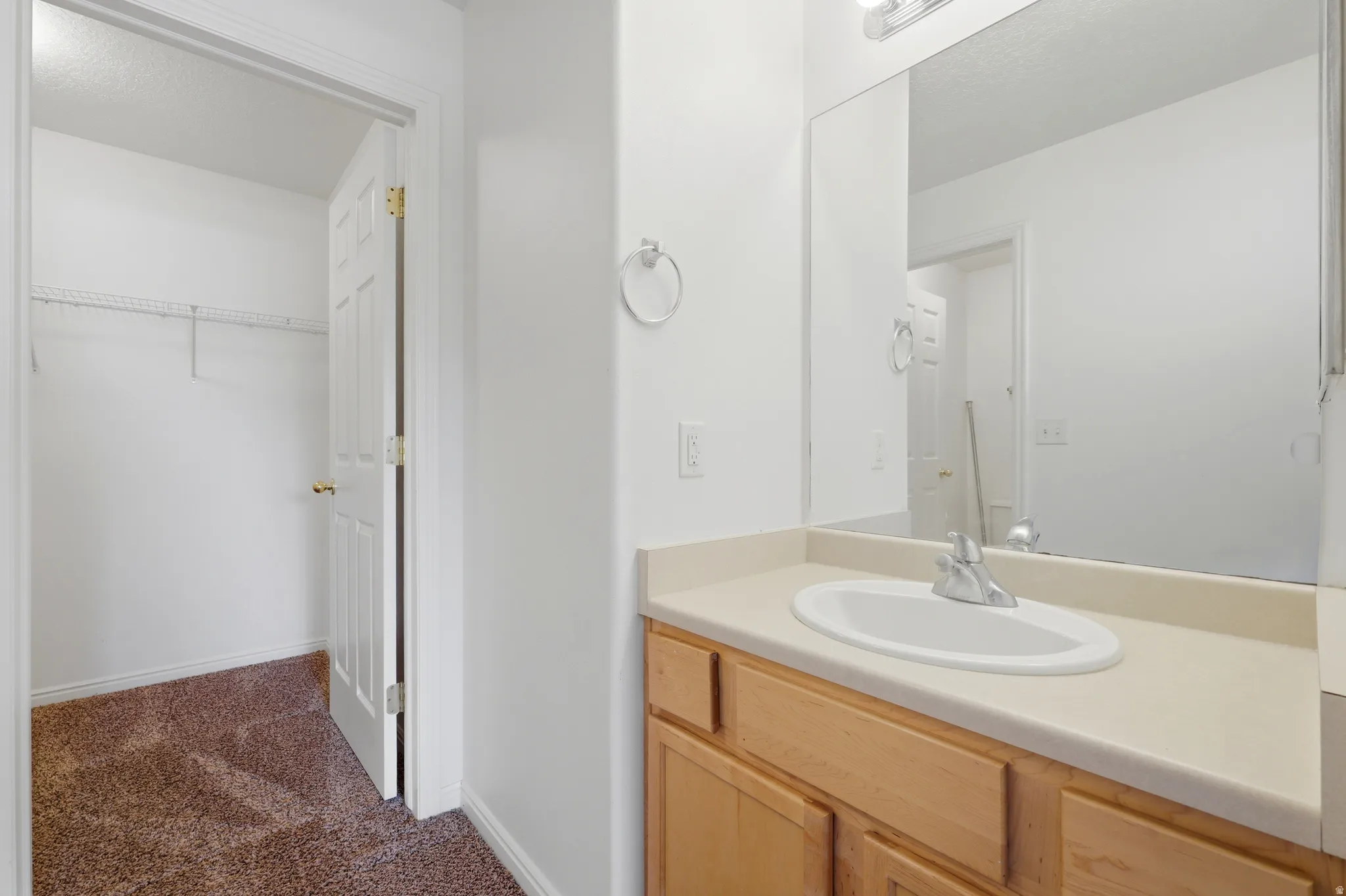 Bathroom vanity featuring a light wood-finish cabinet, integrated sink, and large wall-mounted mirror
