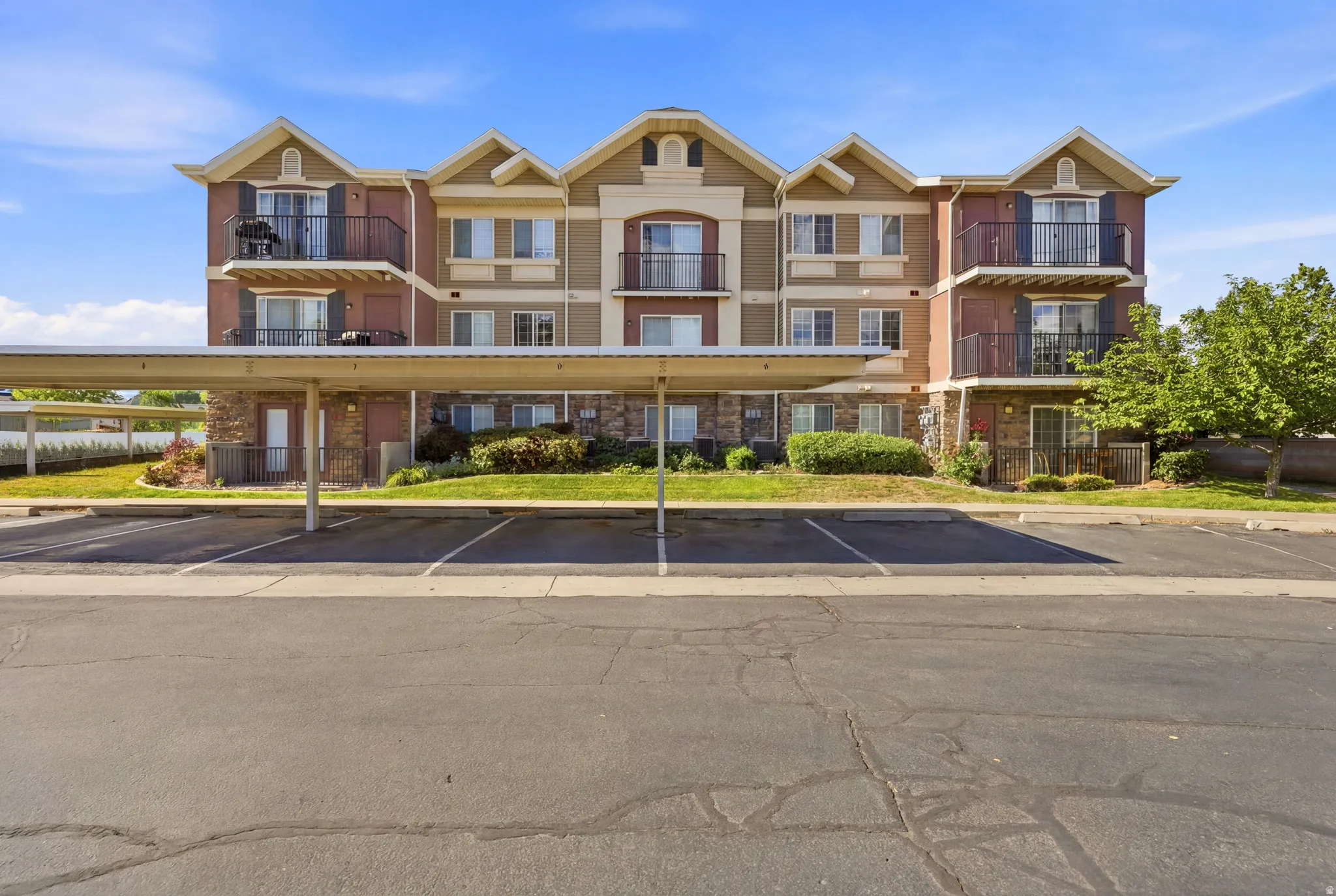Multi-story residential building featuring balconies with wrought iron railings, stone veneer accents, and gabled rooflines