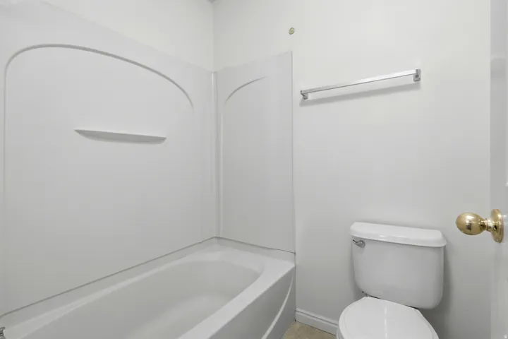 White bathtub and shower surround with an integrated shelf